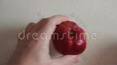 一个人用菜刀把一个红苹果切成两部分。 雄手捧一个有水滴的红苹果..